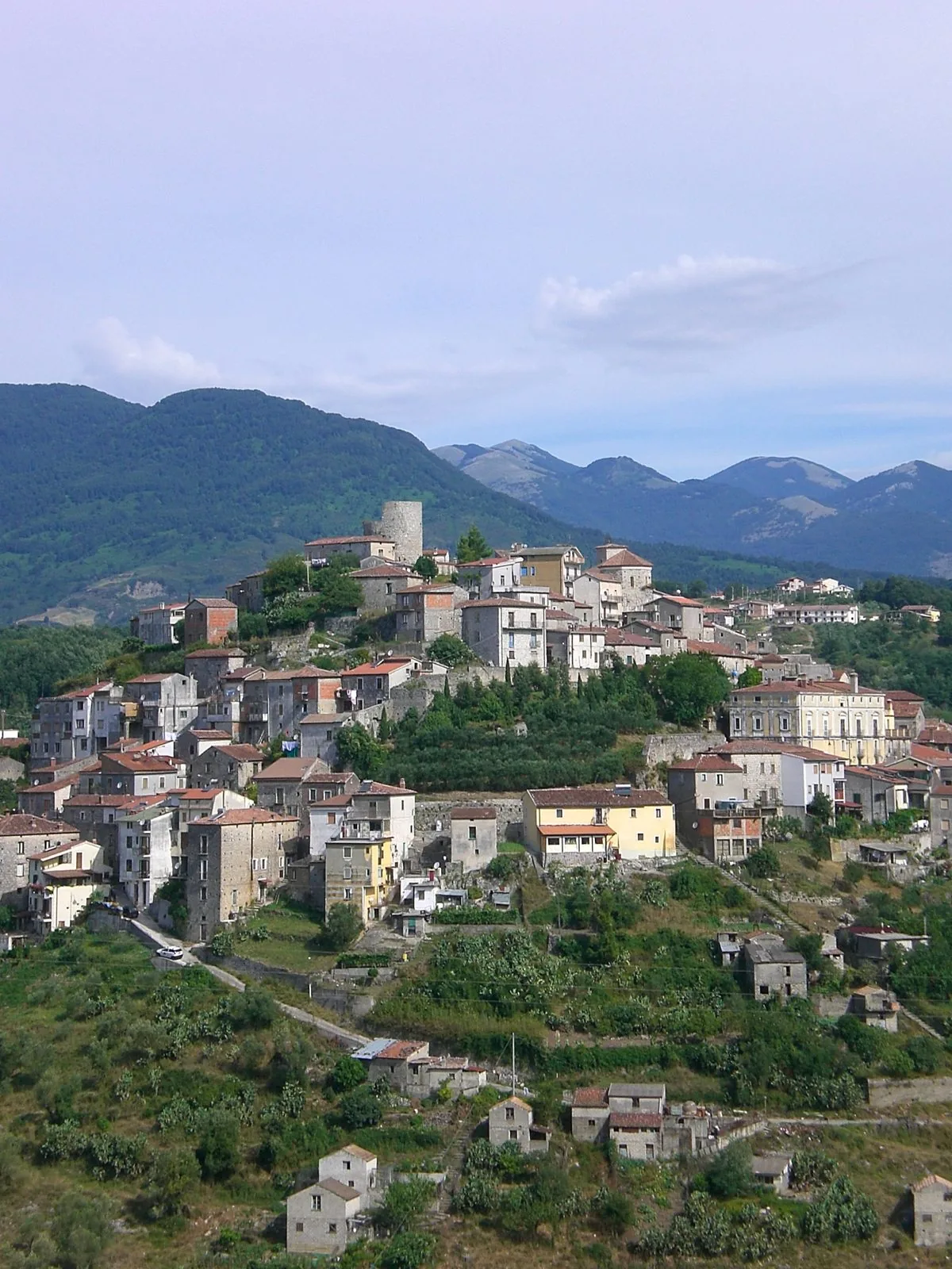 Veduta del borgo di Caselle in Pittari, con le case in pietra sulla collina, la torre e le montagne del Cilento sullo sfondo